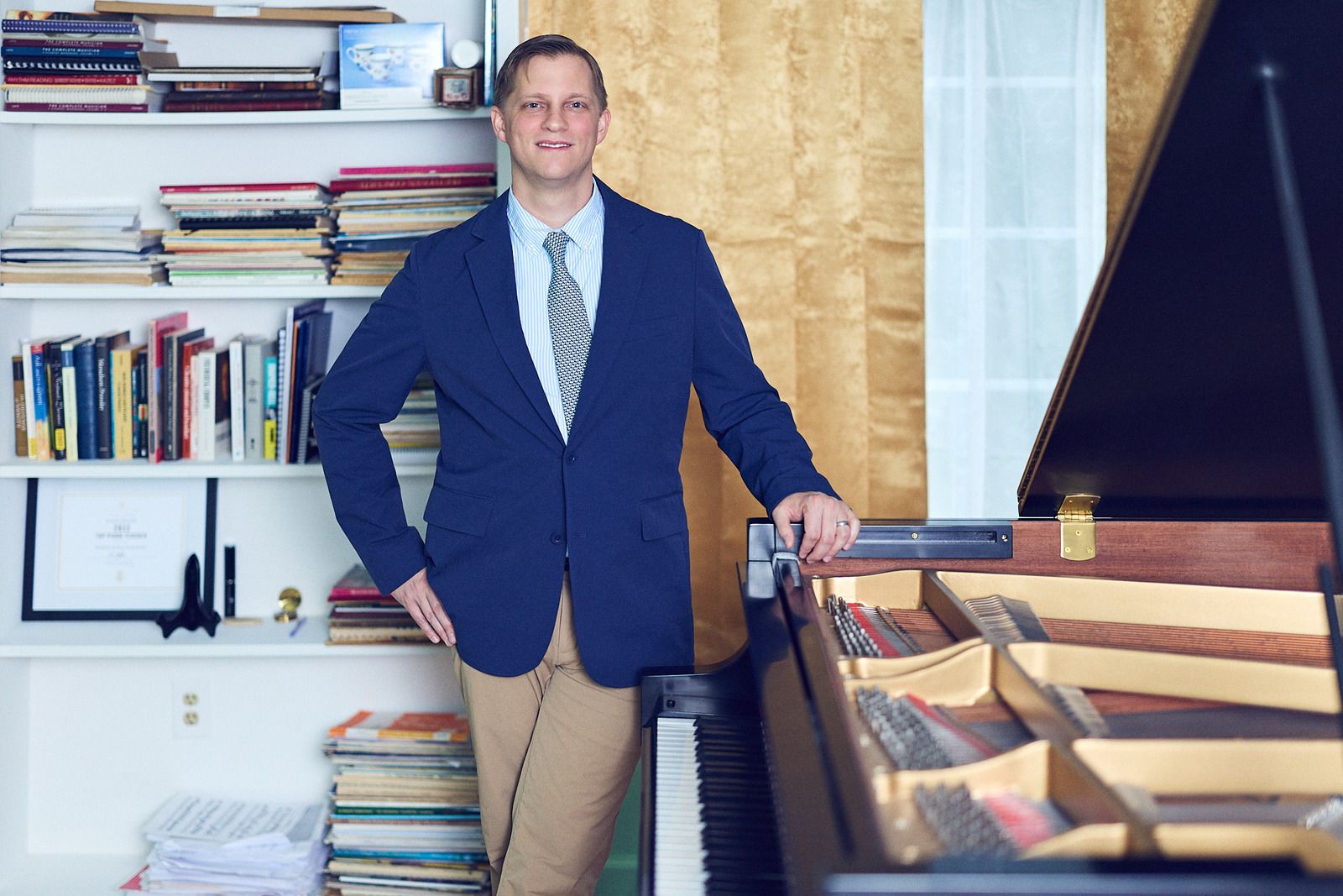 Joe Infurchia standing beside his grand piano in his studio