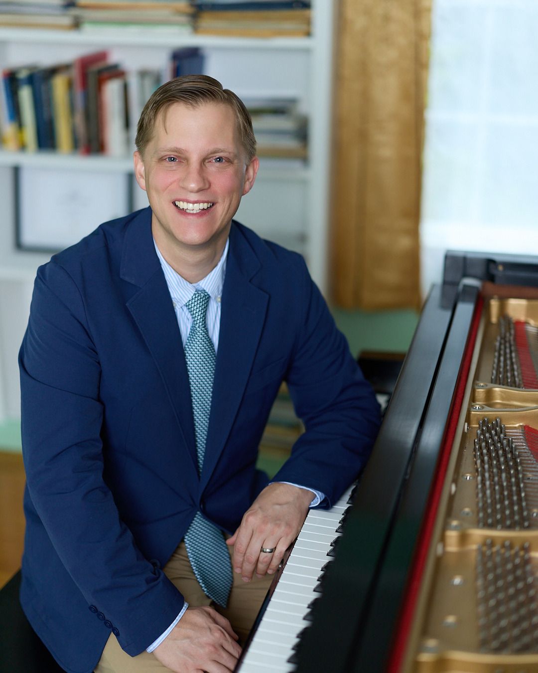Joe Infurchia seated at the piano, smiling